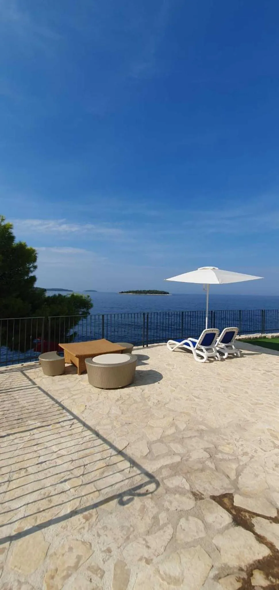 Terrasse ensoleillée avec mobilier de détente et vue sur la mer.