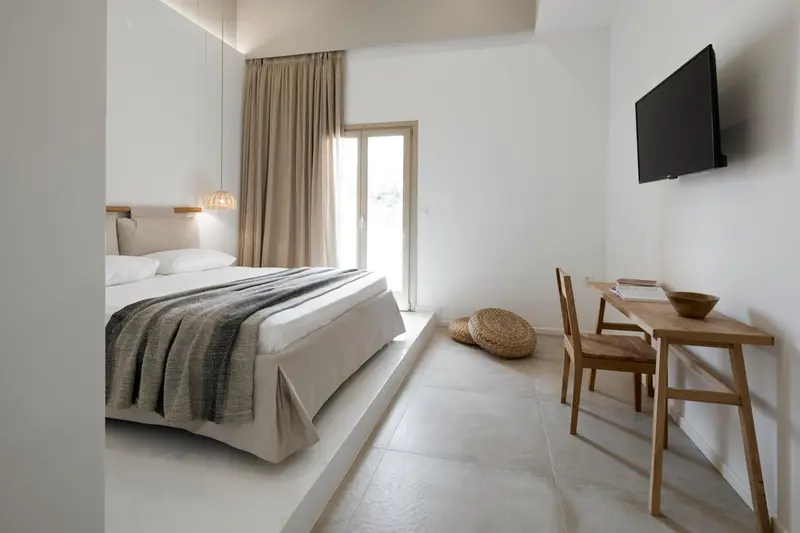 Une chambre lumineuse avec un grand lit et un bureau en bois.