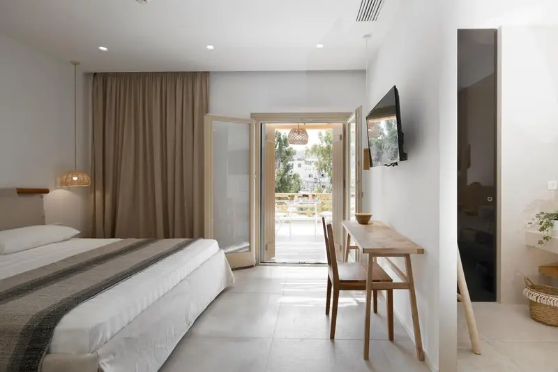 Une chambre lumineuse avec un lit et un bureau donnant sur une terrasse.