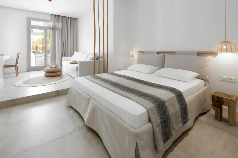 Chambre lumineuse avec un grand lit et un coin salon.
