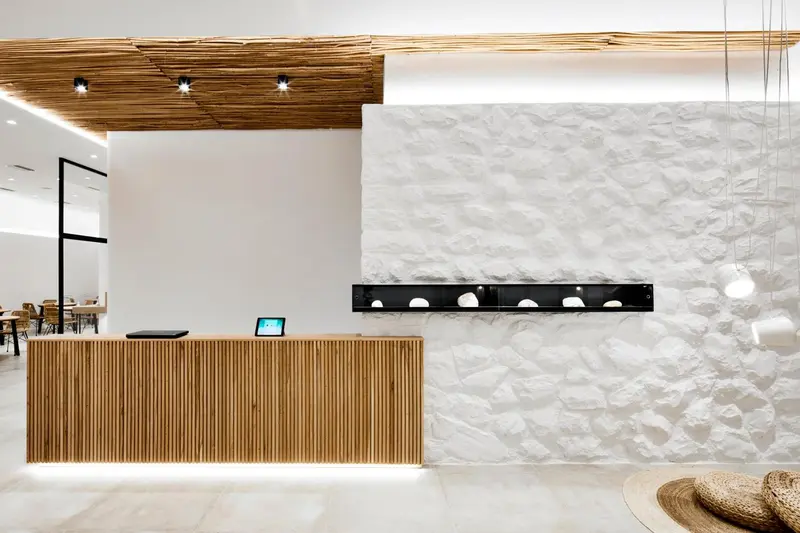 Un comptoir d'accueil en bois clair dans un espace lumineux et moderne.