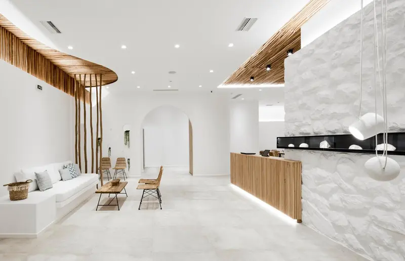 Espace d'accueil lumineux avec un comptoir en bois et un canapé blanc.