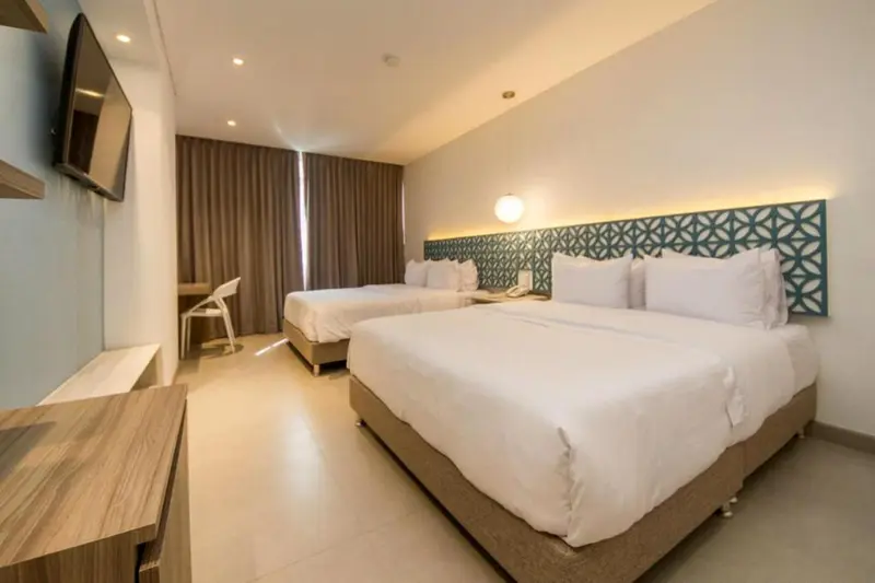 Chambre lumineuse avec deux lits simples et une commode en bois.