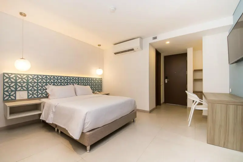 Une chambre lumineuse avec un grand lit et un bureau.