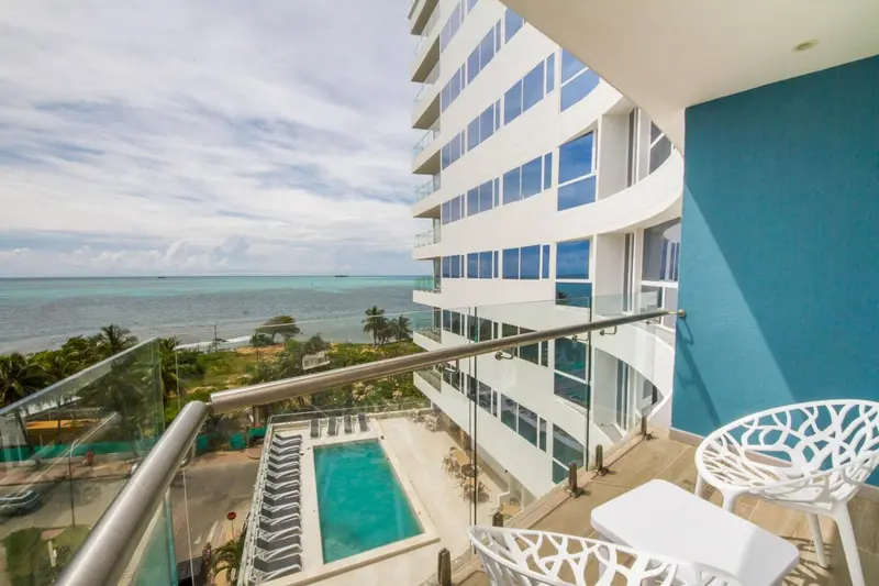 Terrasse avec mobilier blanc donnant sur une piscine et la mer.