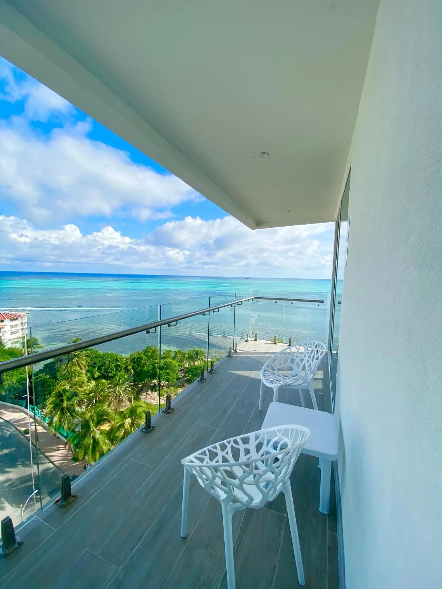 Terrasse avec mobilier blanc donnant sur une vue mer et une végétation luxuriante.