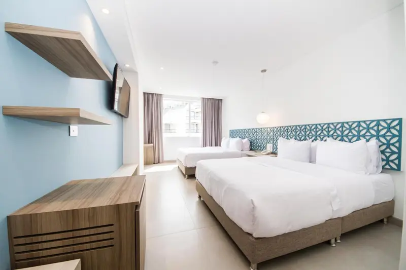 Chambre lumineuse avec deux lits simples et une commode en bois.
