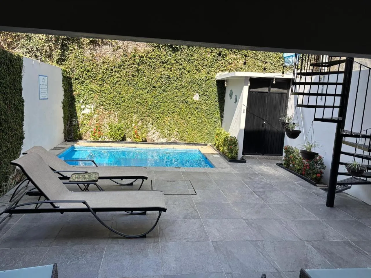 Deux transats gris sont placés devant une petite piscine rectangulaire.