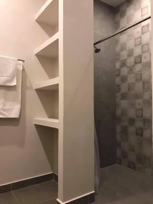 Une douche à l'italienne avec des étagères murales.