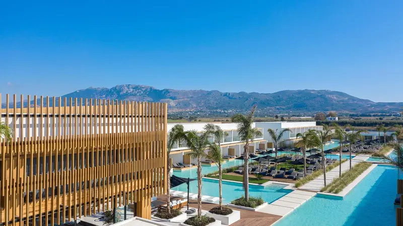 Vue aérienne d'un complexe hôtelier avec des piscines et une végétation luxuriante.