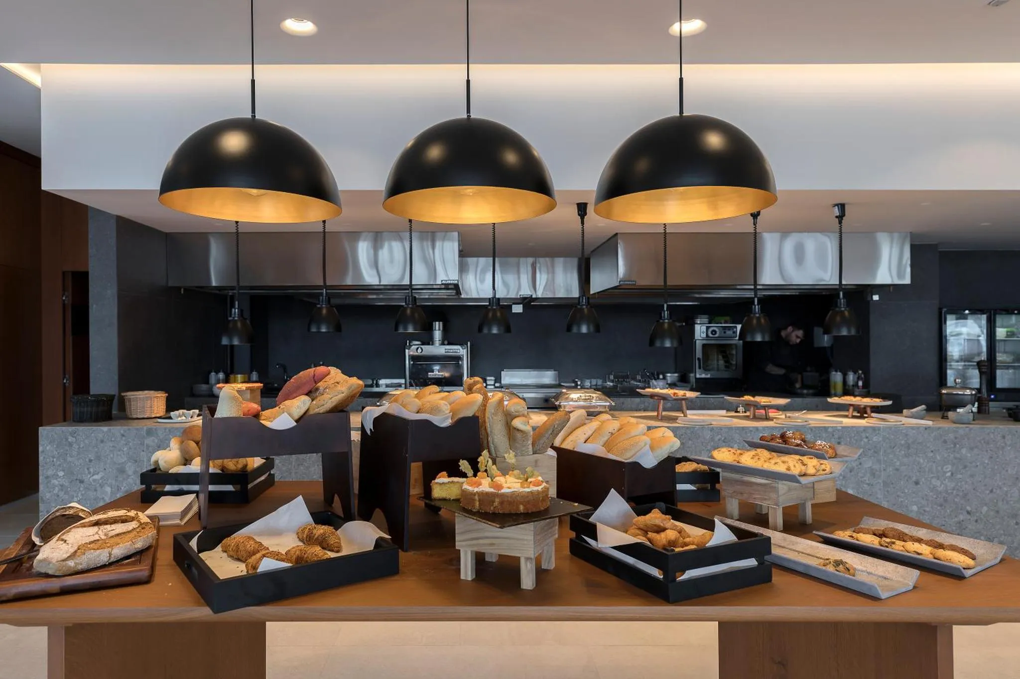 Un buffet propose une variété de pains et de pâtisseries dans un espace lumineux.