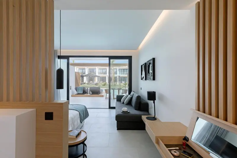 Espace de vie intérieur lumineux avec canapé et accès à une terrasse.