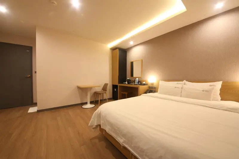 Une chambre lumineuse avec un lit double et un coin repas.