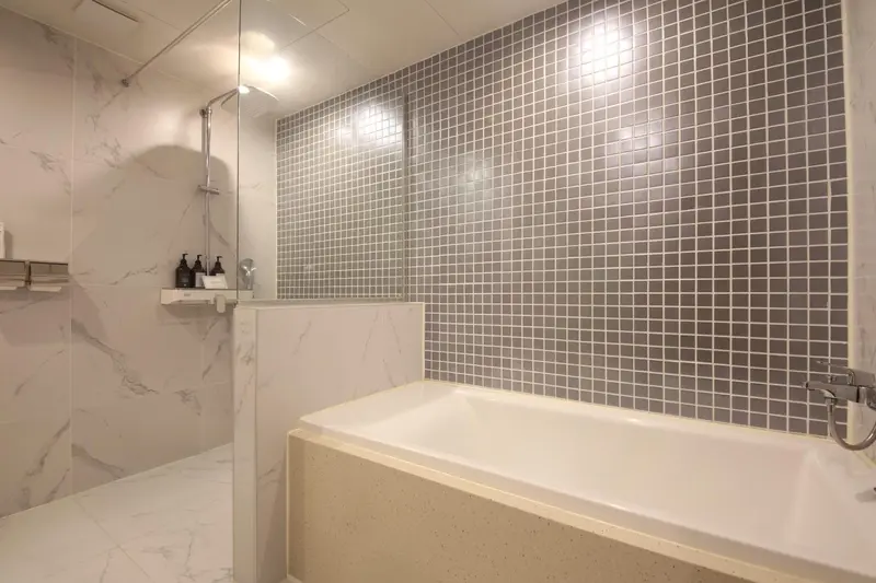 Une baignoire blanche et une douche à l'italienne dans une salle de bain carrelée.