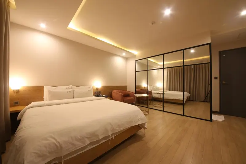 Une chambre lumineuse avec un grand lit et un fauteuil.