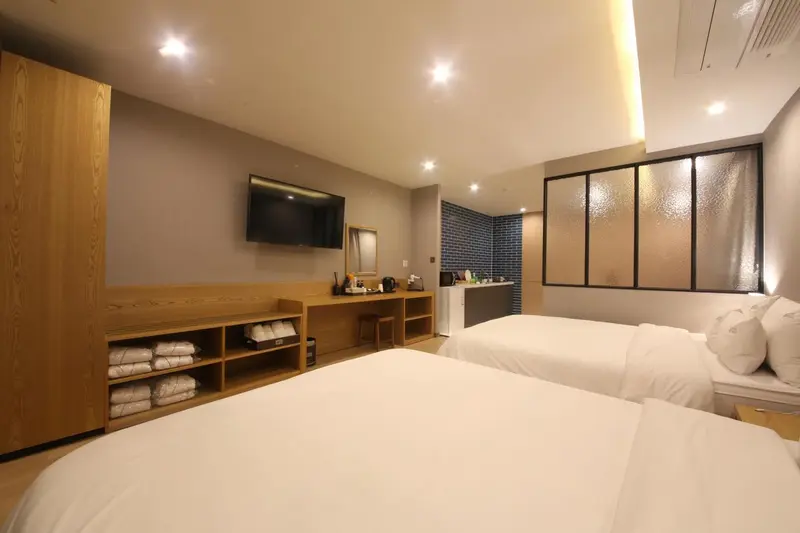 Chambre lumineuse avec deux lits et un espace bureau.