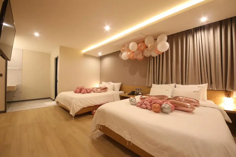 Une chambre d'hôtel avec deux lits doubles décorés de ballons.