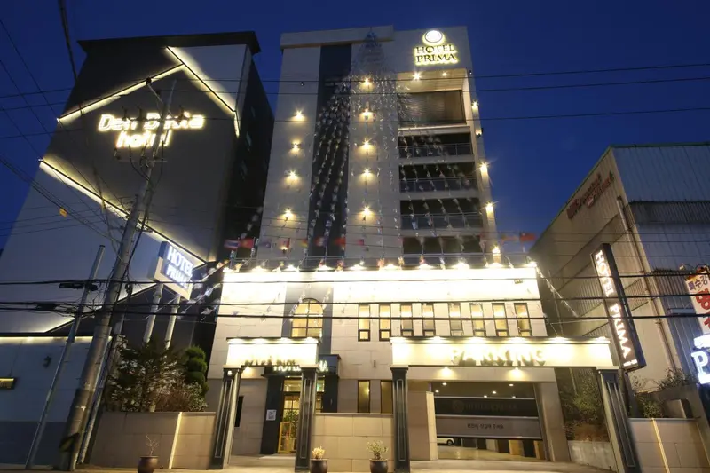 Façade d'un bâtiment illuminé avec une entrée et des enseignes lumineuses.