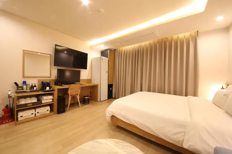 Une chambre lumineuse avec deux lits et un téléviseur mural.
