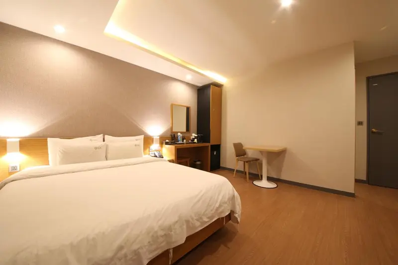 Une chambre lumineuse avec un grand lit et un bureau.