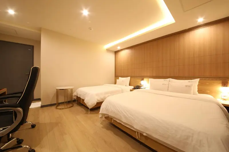 Une chambre d'hôtel lumineuse avec deux lits simples et un coin bureau.