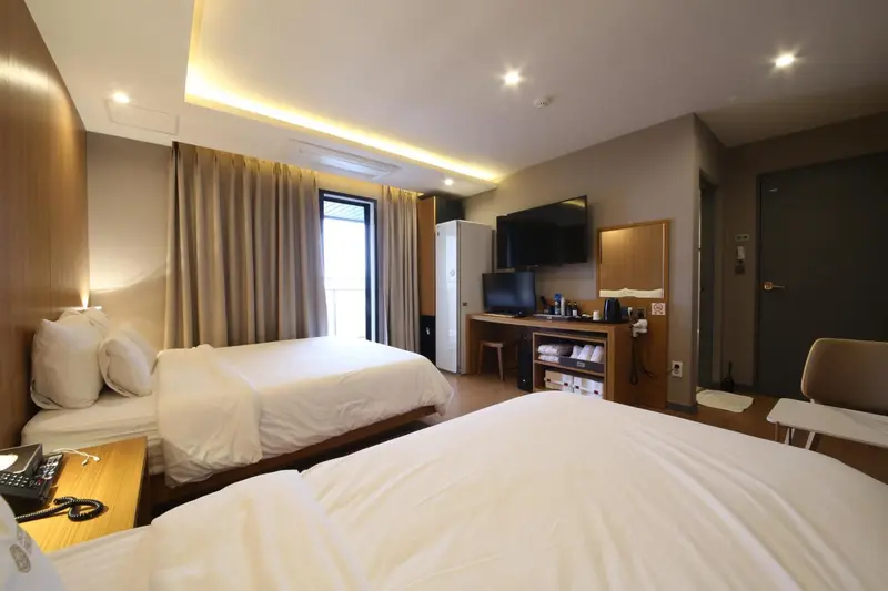 Une chambre d'hôtel avec deux lits simples et un téléviseur mural.