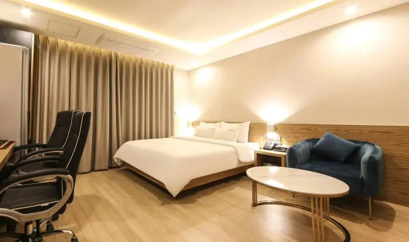 Une chambre lumineuse avec un lit double et un coin salon.