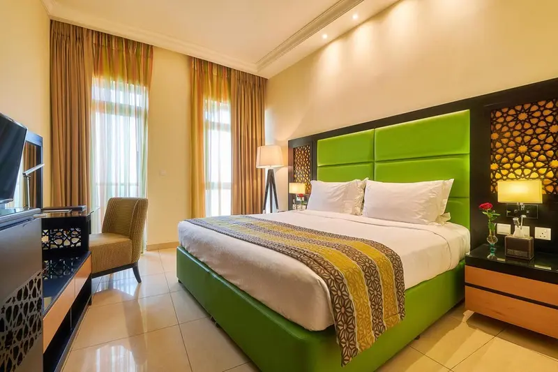 Une chambre d'hotel lumineuse avec un grand lit et un fauteuil.