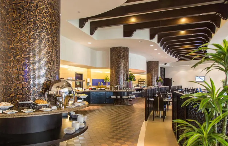 Un buffet de plats variés est présenté dans une salle lumineuse et moderne.