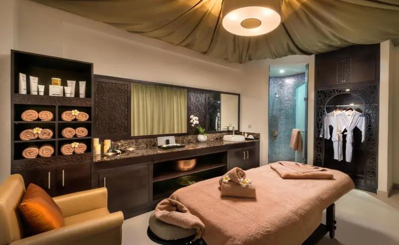Espace de soins avec table de massage et étagères de produits.