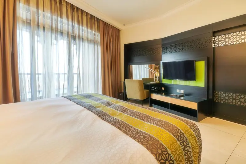Une chambre d'hôtel moderne avec un grand lit et un téléviseur mural.