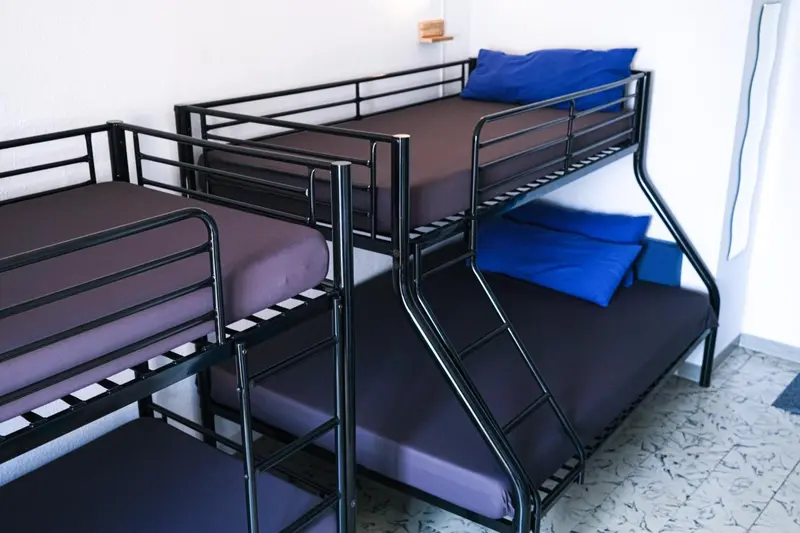 Lits superposés avec oreillers bleus dans une chambre sobre.