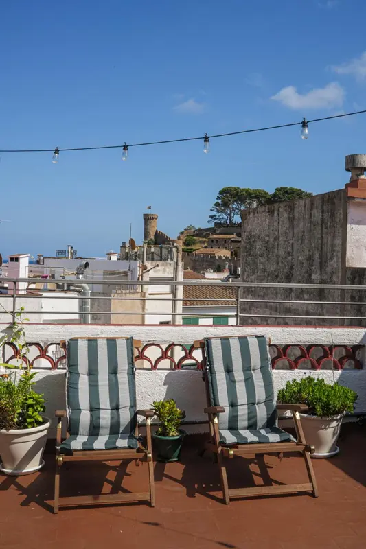 Terrasse avec chaises longues et vue sur la ville.