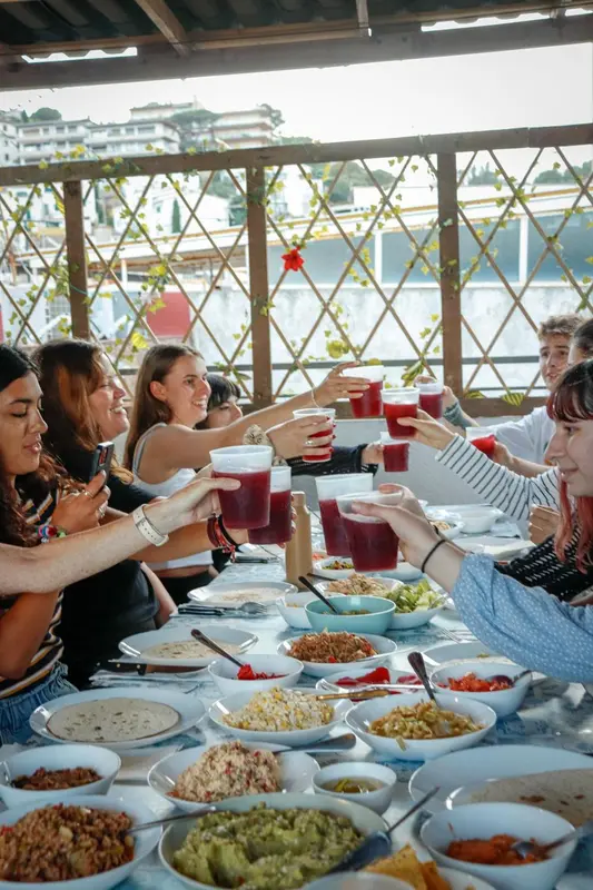 Une table conviviale est dressée en plein air avec des convives levant leurs verres.