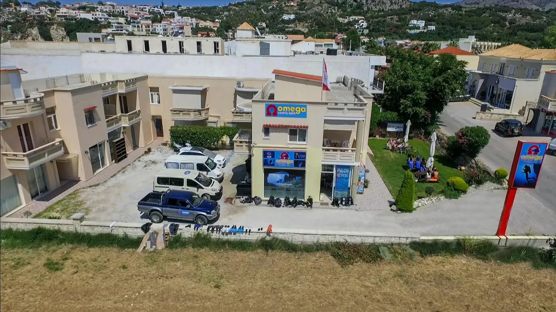 Vue aérienne d'un bâtiment blanc avec des véhicules et des personnes devant.