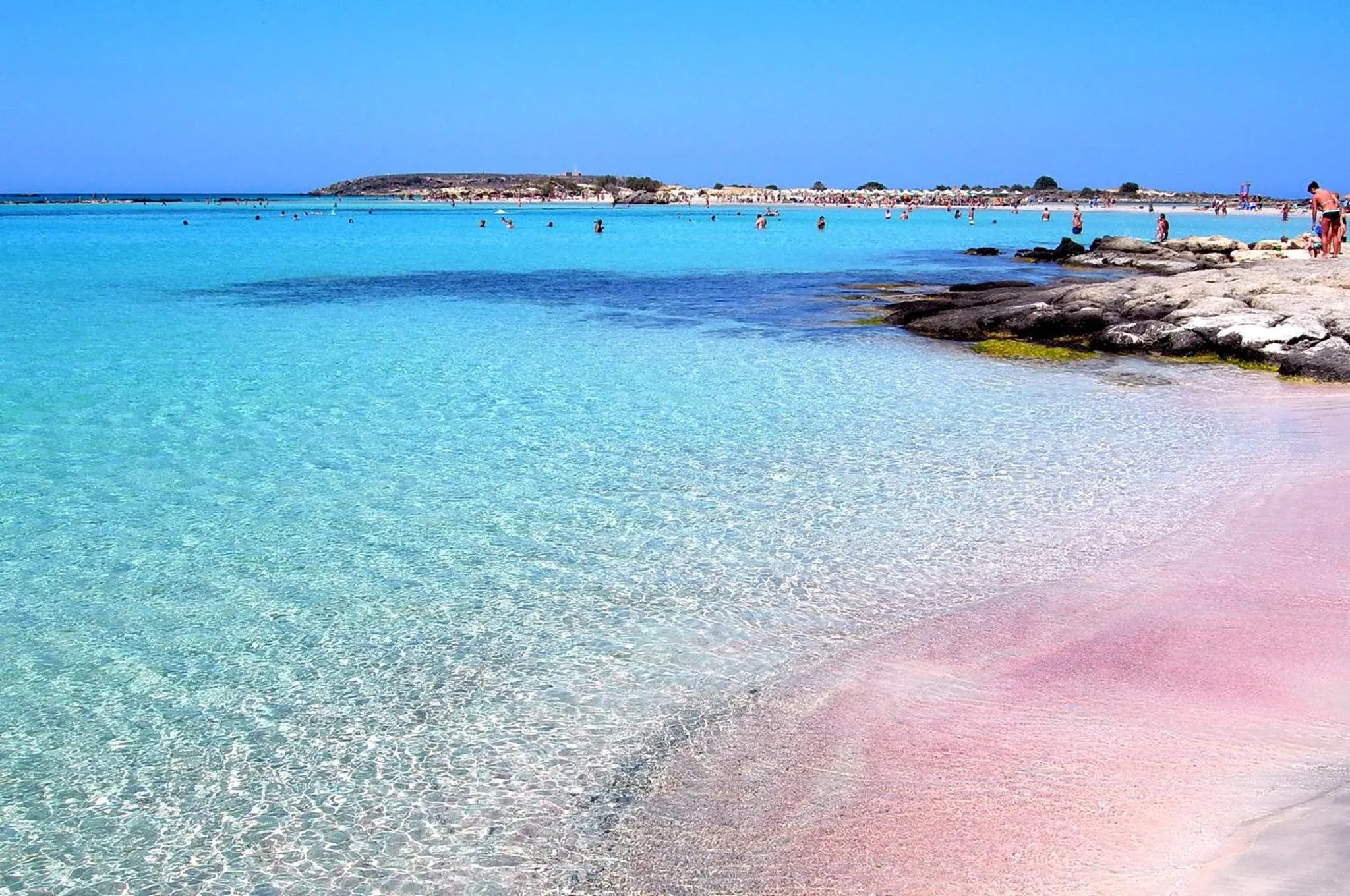 Plage de sable blanc bordée d'une eau turquoise et translucide.