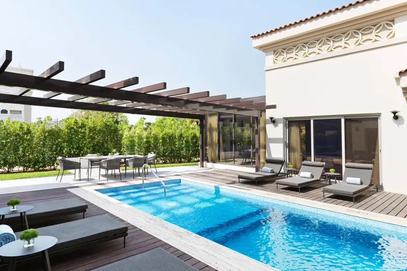 Une piscine privée avec terrasse et mobilier de jardin.