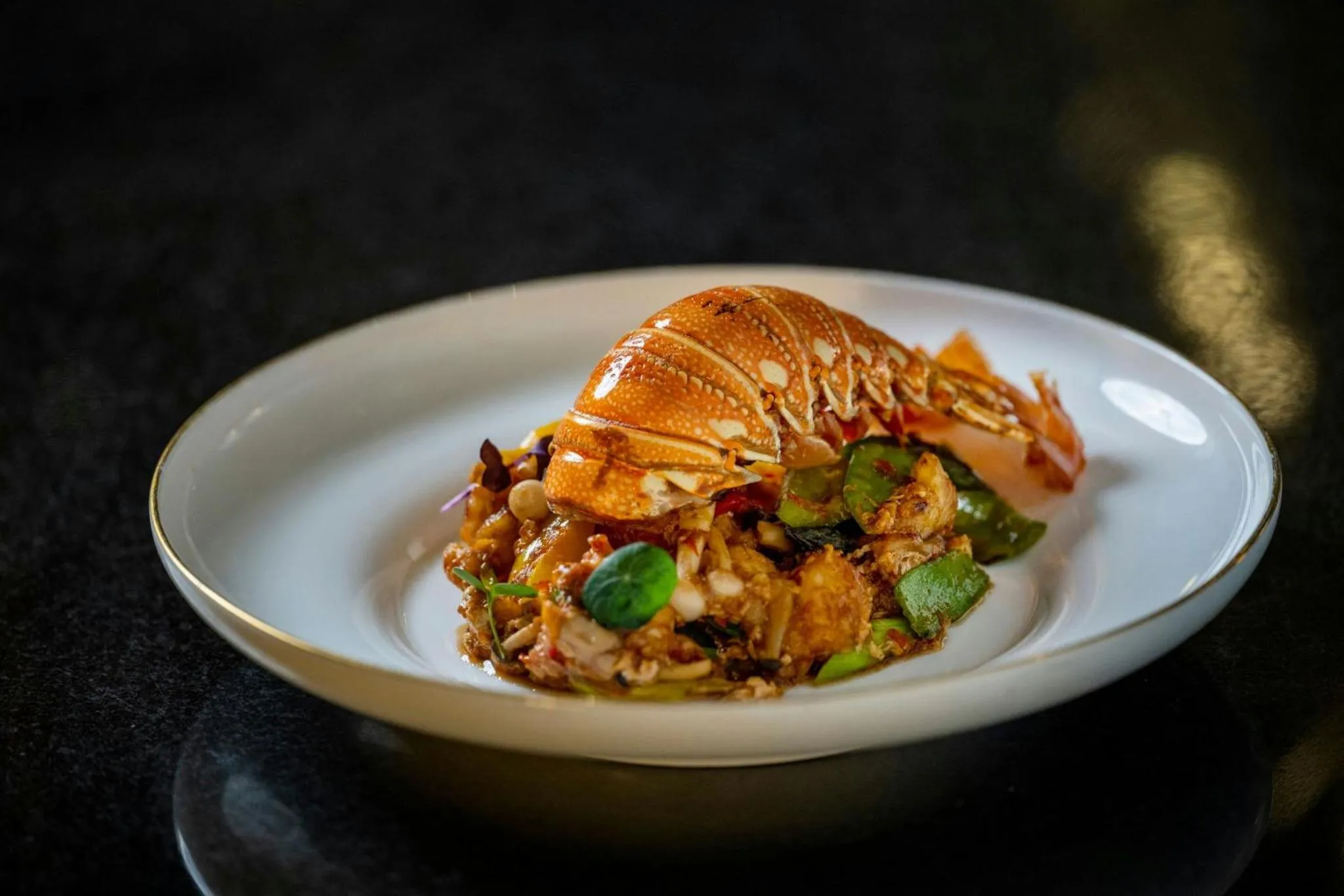 Assiette de homard et de riz présentée sur une table sombre.