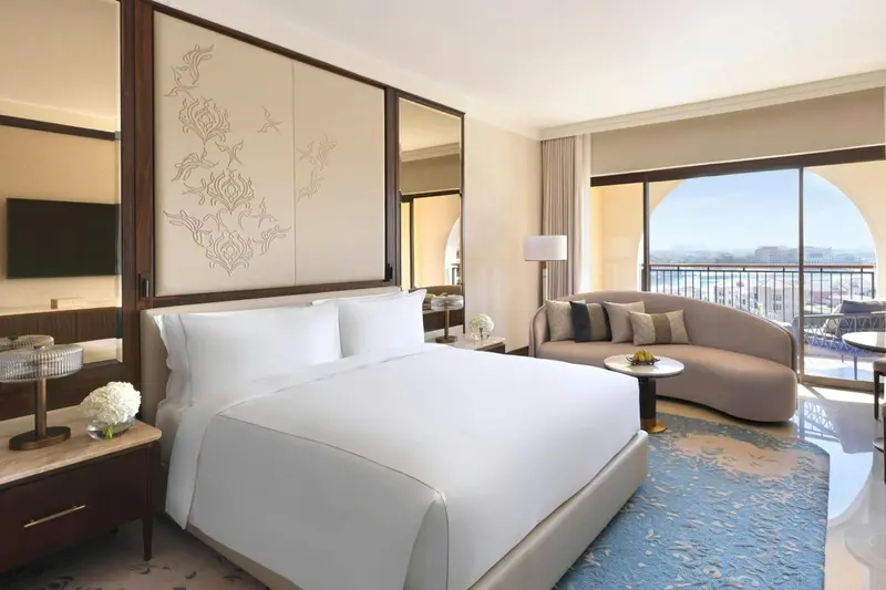 Une chambre lumineuse avec un grand lit et un coin salon près d'une fenêtre.