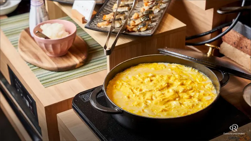 Un plat d'œufs brouillés cuit dans une poêle sur une plaque de cuisson.