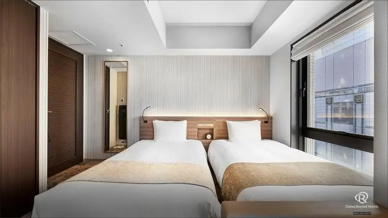 Une chambre avec deux lits simples et une fenêtre.
