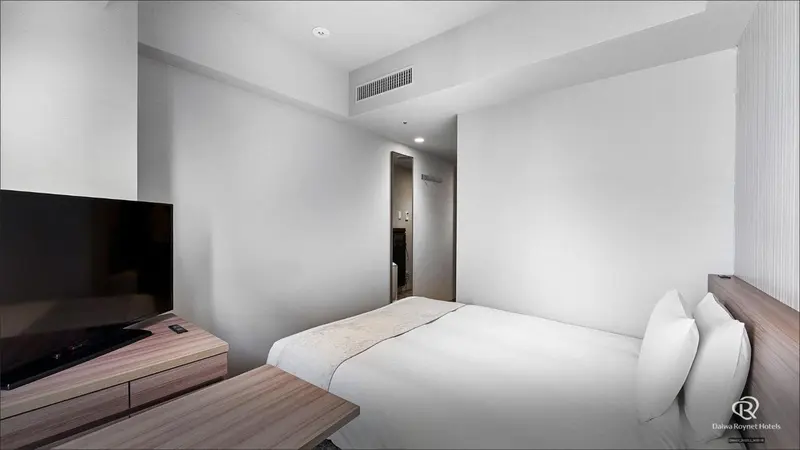 Une chambre lumineuse avec un lit et un meuble télévision.
