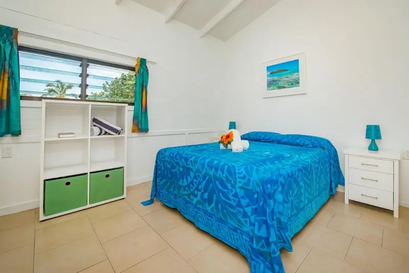 Une chambre lumineuse avec un lit recouvert d'une couverture bleue et un tableau mural.
