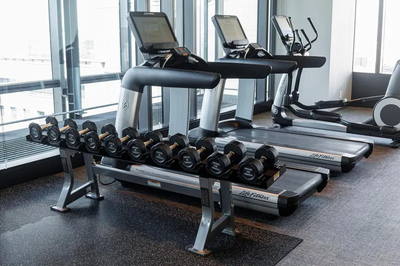 Une salle de sport avec des tapis de course et des haltères.