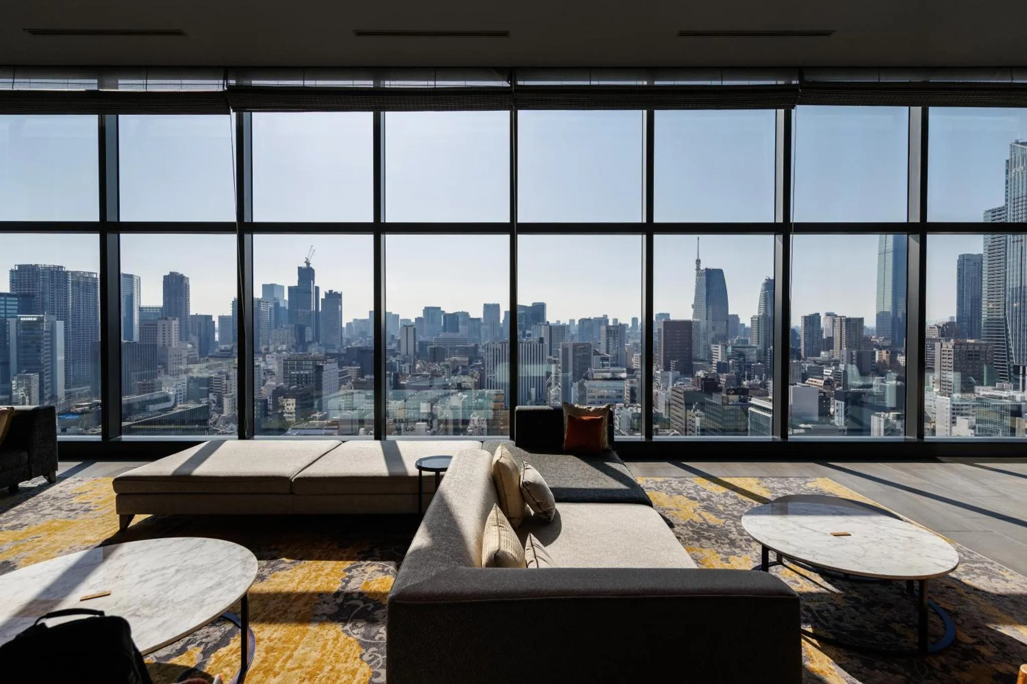 Espace de détente avec canapés et tables basses donnant sur une vue urbaine.