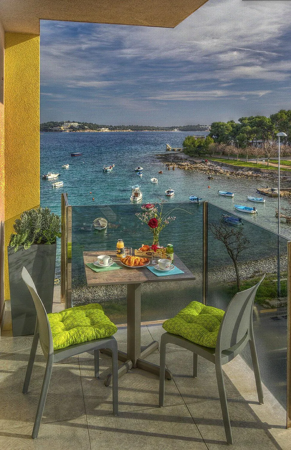Une table avec un petit-déjeuner est mise en scène sur une terrasse avec vue sur la mer.