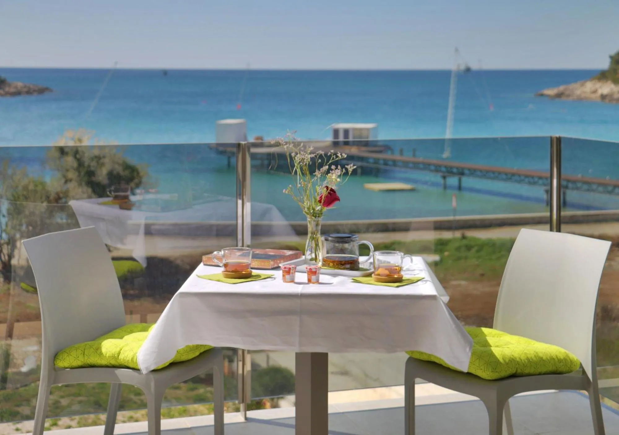 Une table est dressée pour deux sur une terrasse avec vue sur la mer.