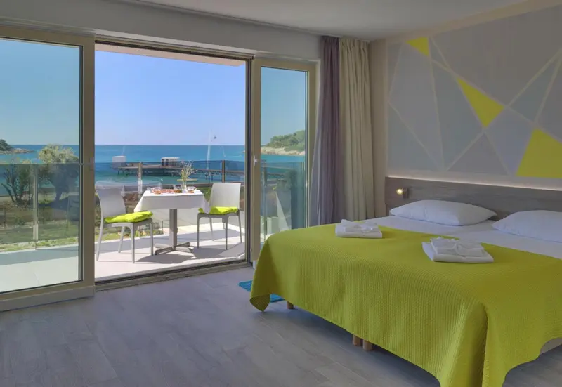 Chambre lumineuse avec vue sur la mer depuis une terrasse.