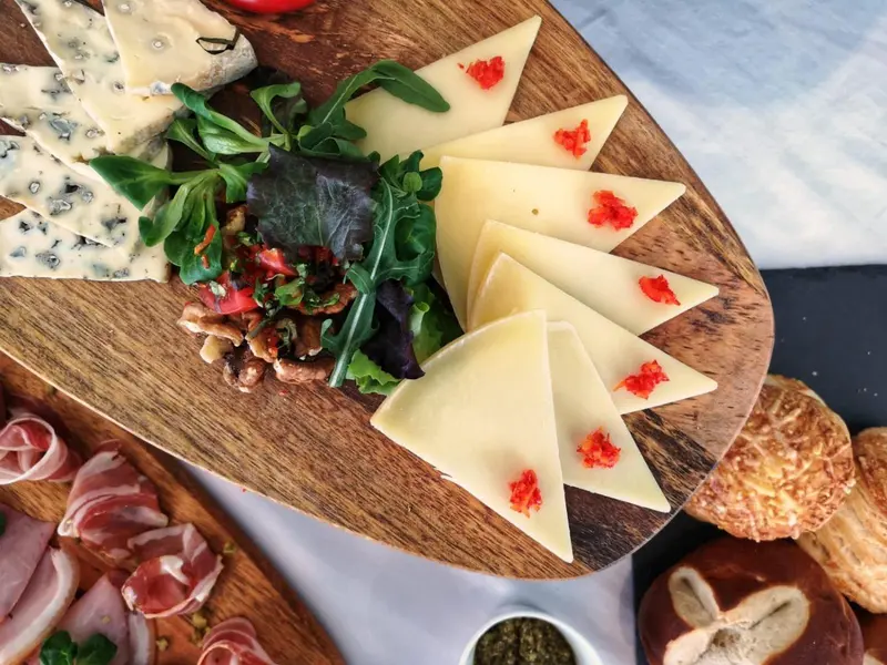 Assortiment de fromages, charcuteries et accompagnements sur une planche en bois.