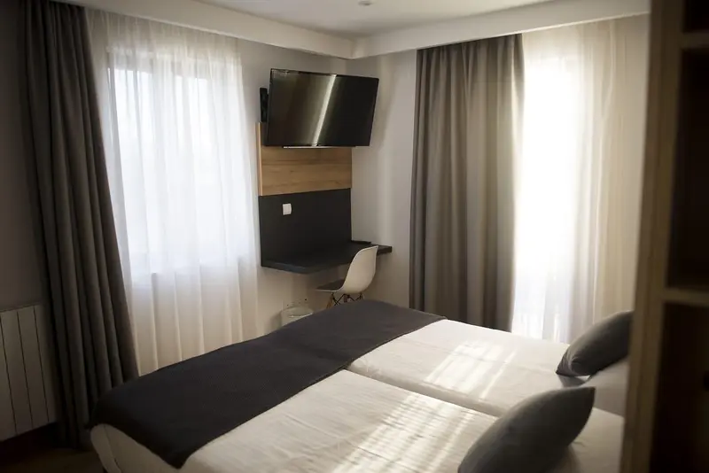 Une chambre avec un lit double et un téléviseur mural.